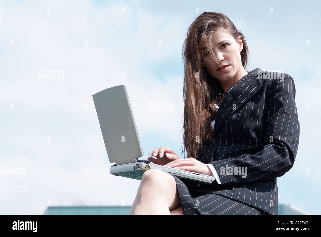 Une femme regarde la caméra en tant qu'elle travaille sur l'ordinateur portable Banque D'Images