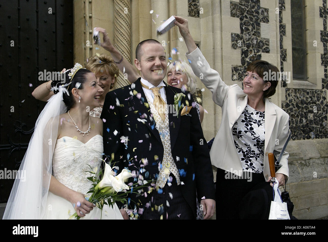 Mariés à uk avec des invités de mariage confettis jeter Banque D'Images