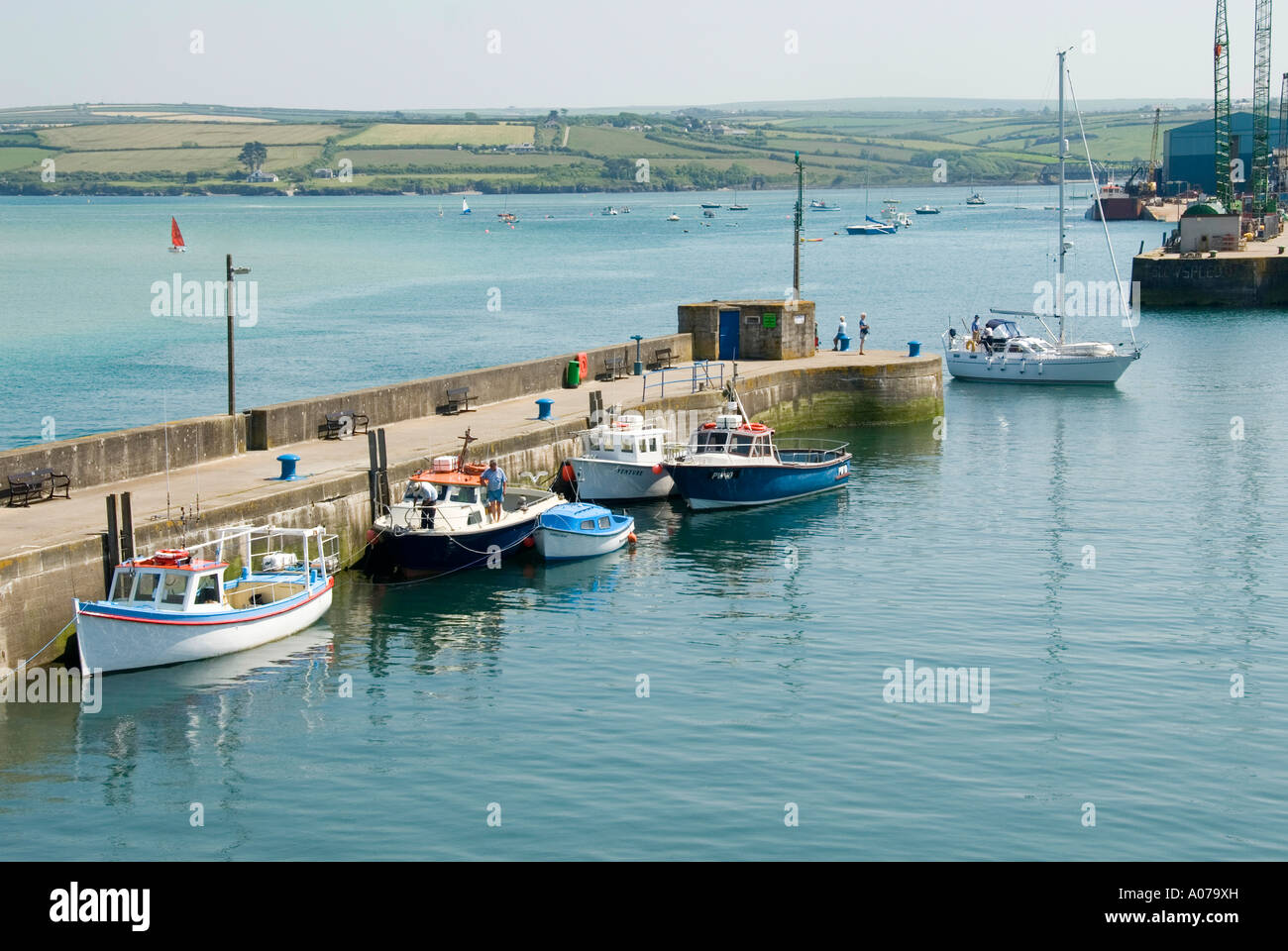 Yacht à voile entre dans le port de Padstow Cornish le fleuve de l'estuaire de Camel sur la côte nord des Cornouailles à rejoindre les petits bateaux amarrés le long mur du port Banque D'Images