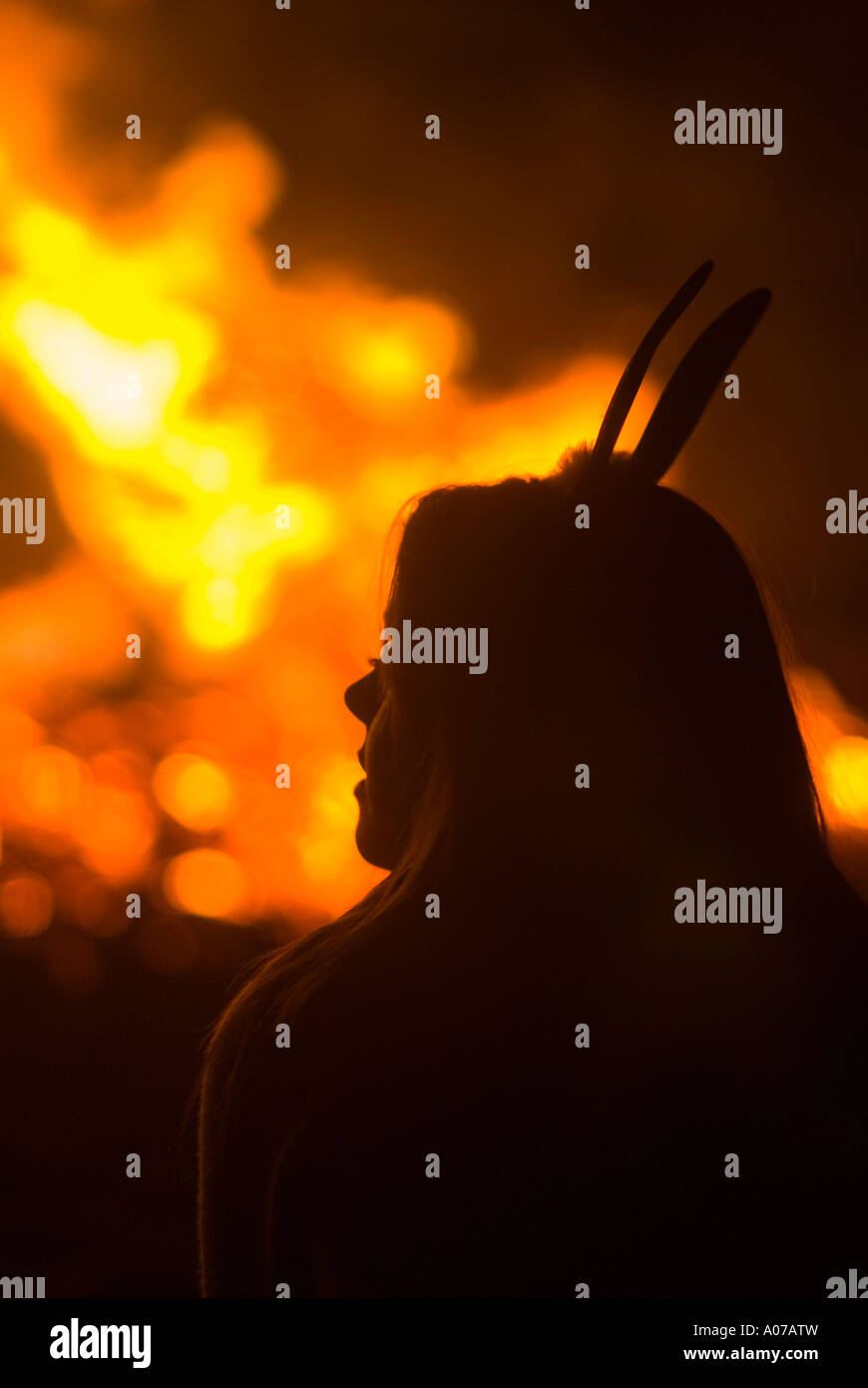 Silhouette d'une jeune femme avec des oreilles de lapin devant un feu Banque D'Images