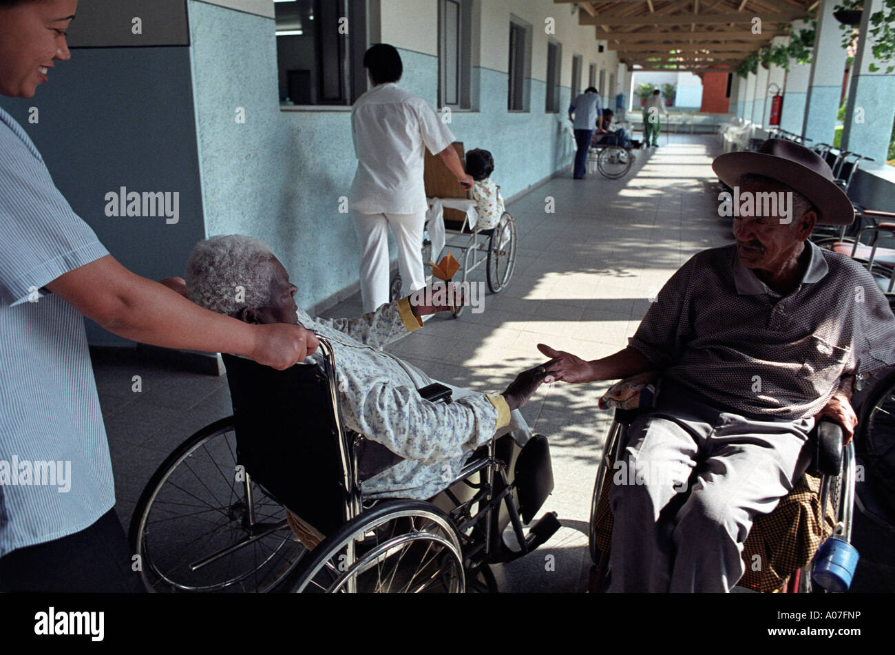 L'hôpital gériatrique une vieille femme noire donne une fleur en papier à un collègue masculin blanc Banque D'Images