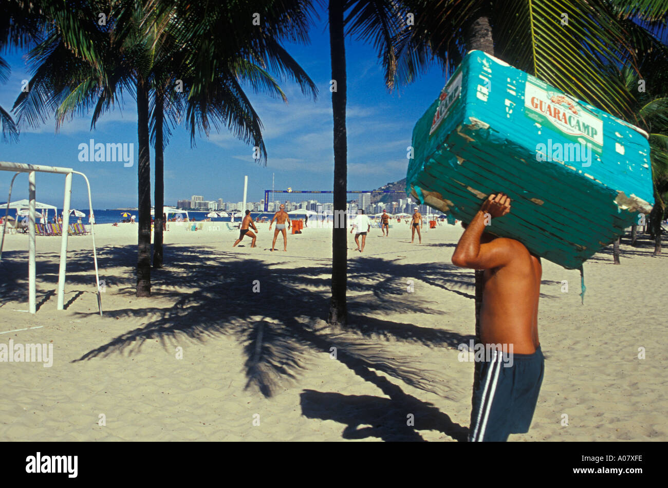 Vendeur de plage porte fort de boissons de personnes jouent futivolei footvolley palmiers plage Copacabana Rio de Janeiro Brésil Banque D'Images
