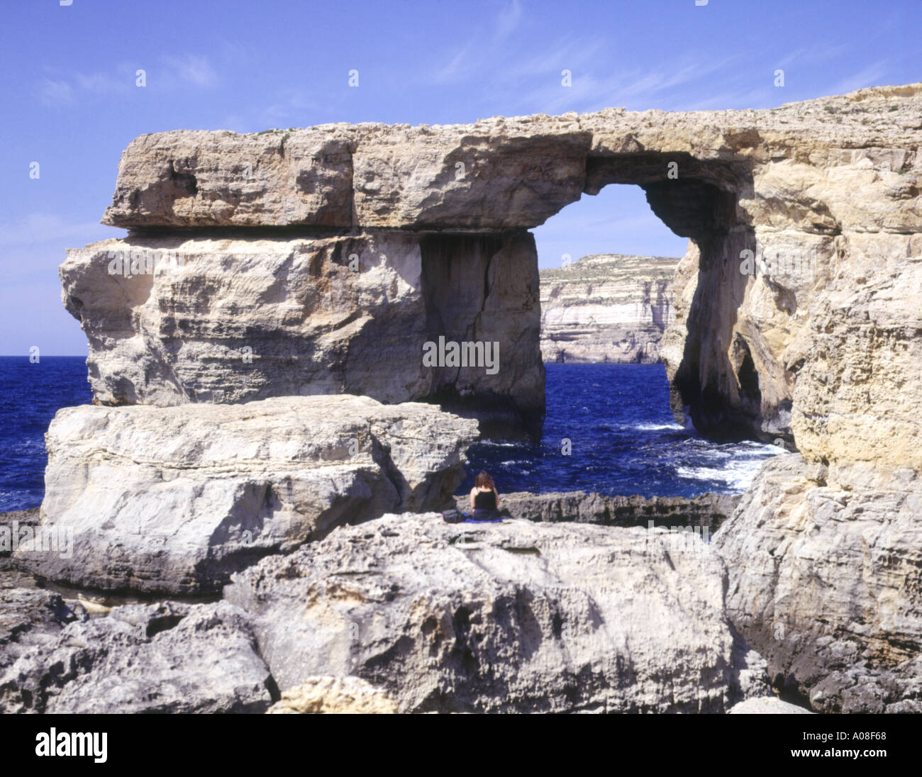 Fenêtre d'Azur dh POINT DWEJRA GOZO Girl sitting on rock à la mer à la roche naturelle arch Banque D'Images