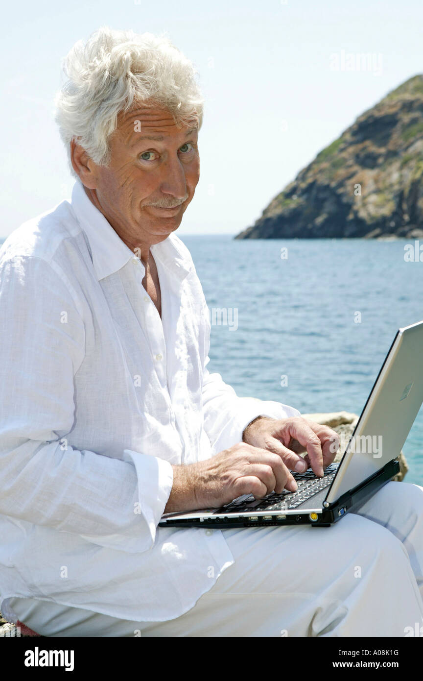Mann mit Senior Coffre am Meer, senior homme avec un ordinateur portable à côté de la mer Banque D'Images