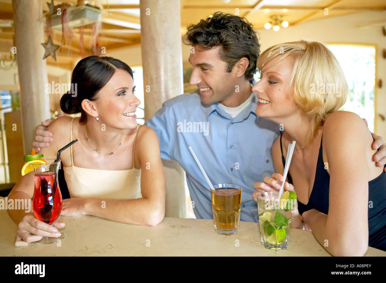 Mann flirtet mit zwei Frauen an der Bar de l