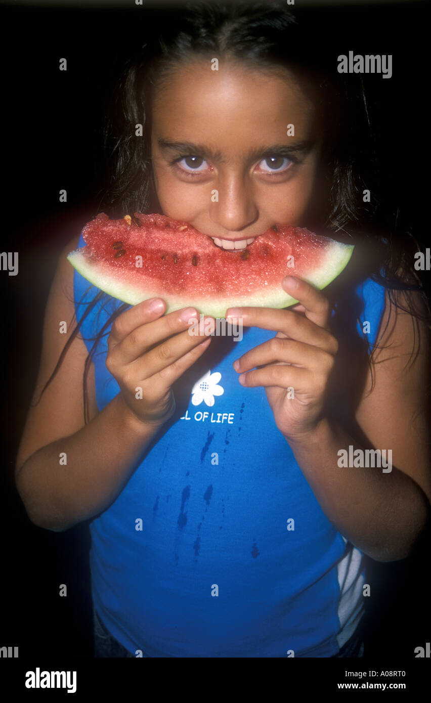 Heureux à la smiling young girl eating a fresh watermelon sur fond noir Banque D'Images