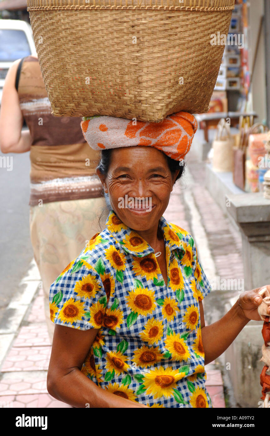 Femme souriante, exerçant son panier en osier sur la tête, Ubud, Bali Indonésie Banque D'Images