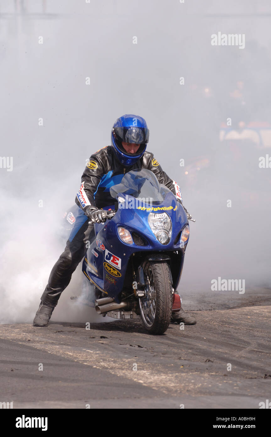 Motocycliste de faire un burnout au début d'une course de glisser à santa pod Banque D'Images