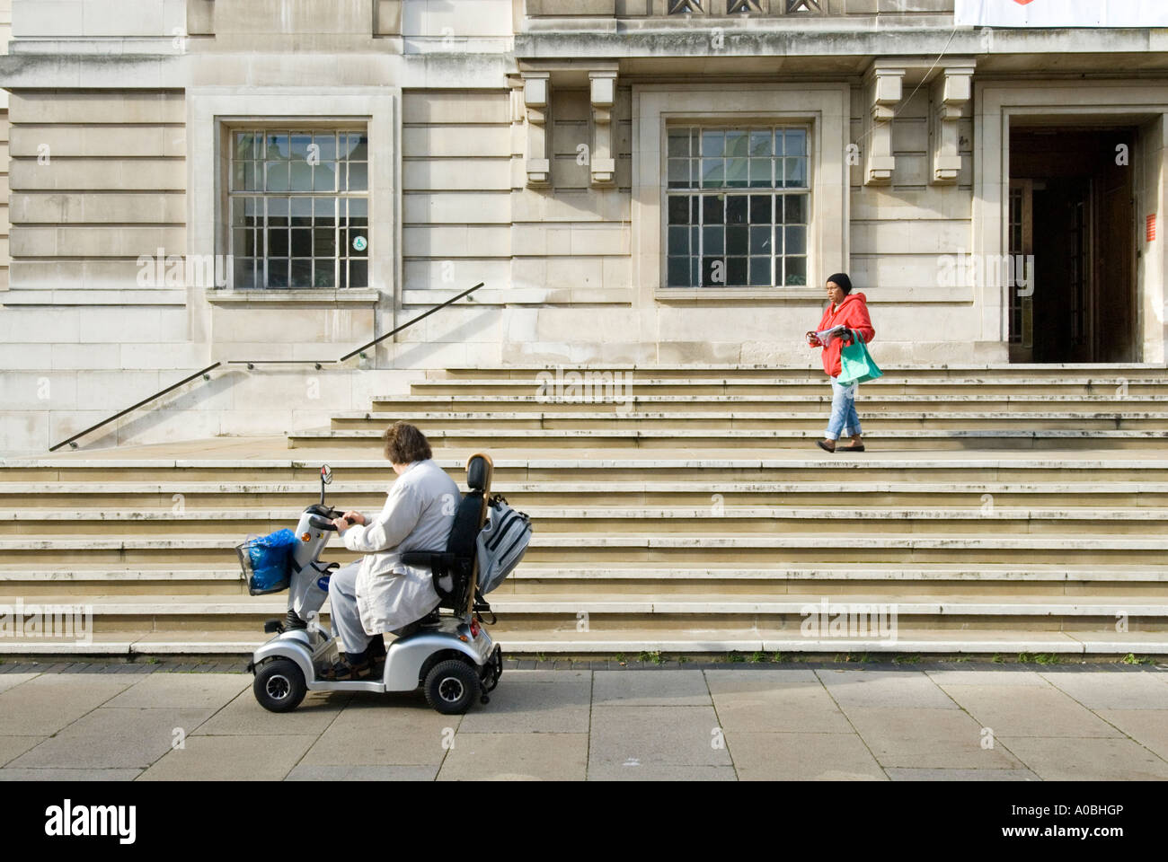 Femme en scooter de mobilité au pied des marches de l'Hôtel de Ville de Hackney, Londres, Angleterre, Royaume-Uni Banque D'Images