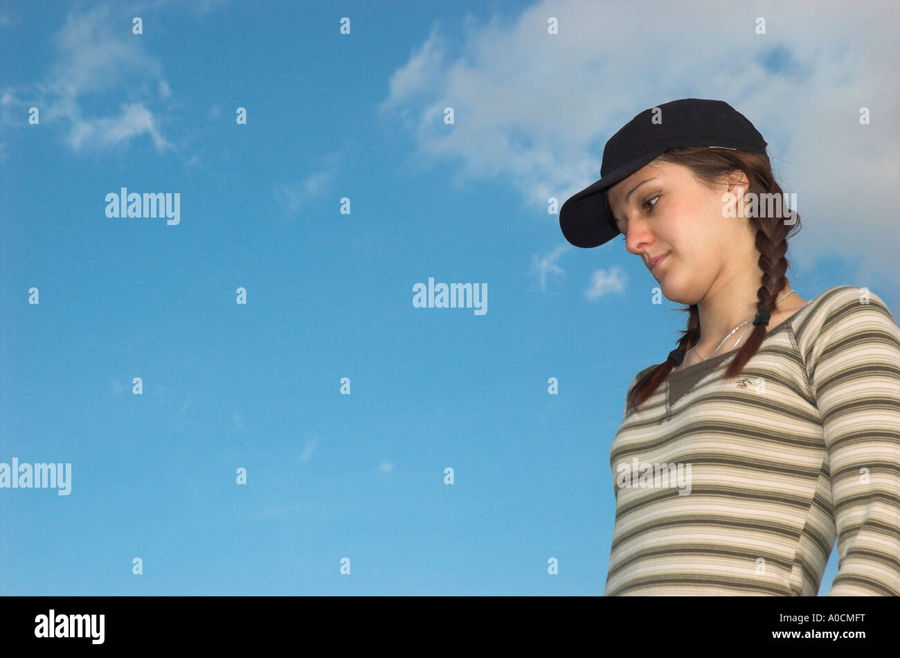 Jeune femme aux tresses wearing cap standing outdoors Banque D'Images
