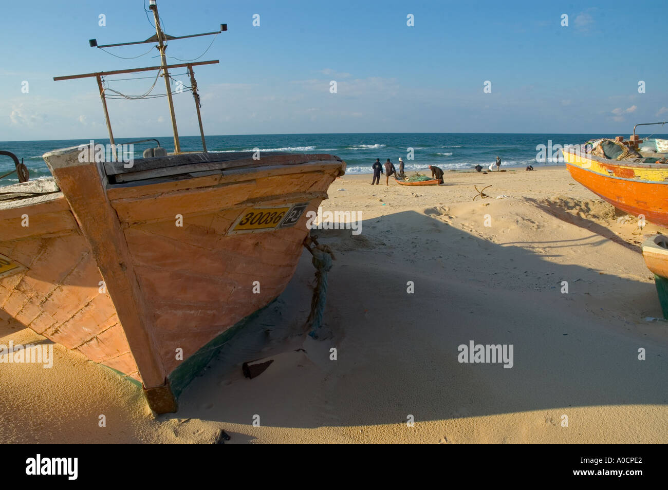 La bande de Gaza al mawassi Gush Katif enclave bateau de pêche à sec sur la plage la moitié enterré dans le sable avec les pêcheurs et la mer dans bkgd Banque D'Images