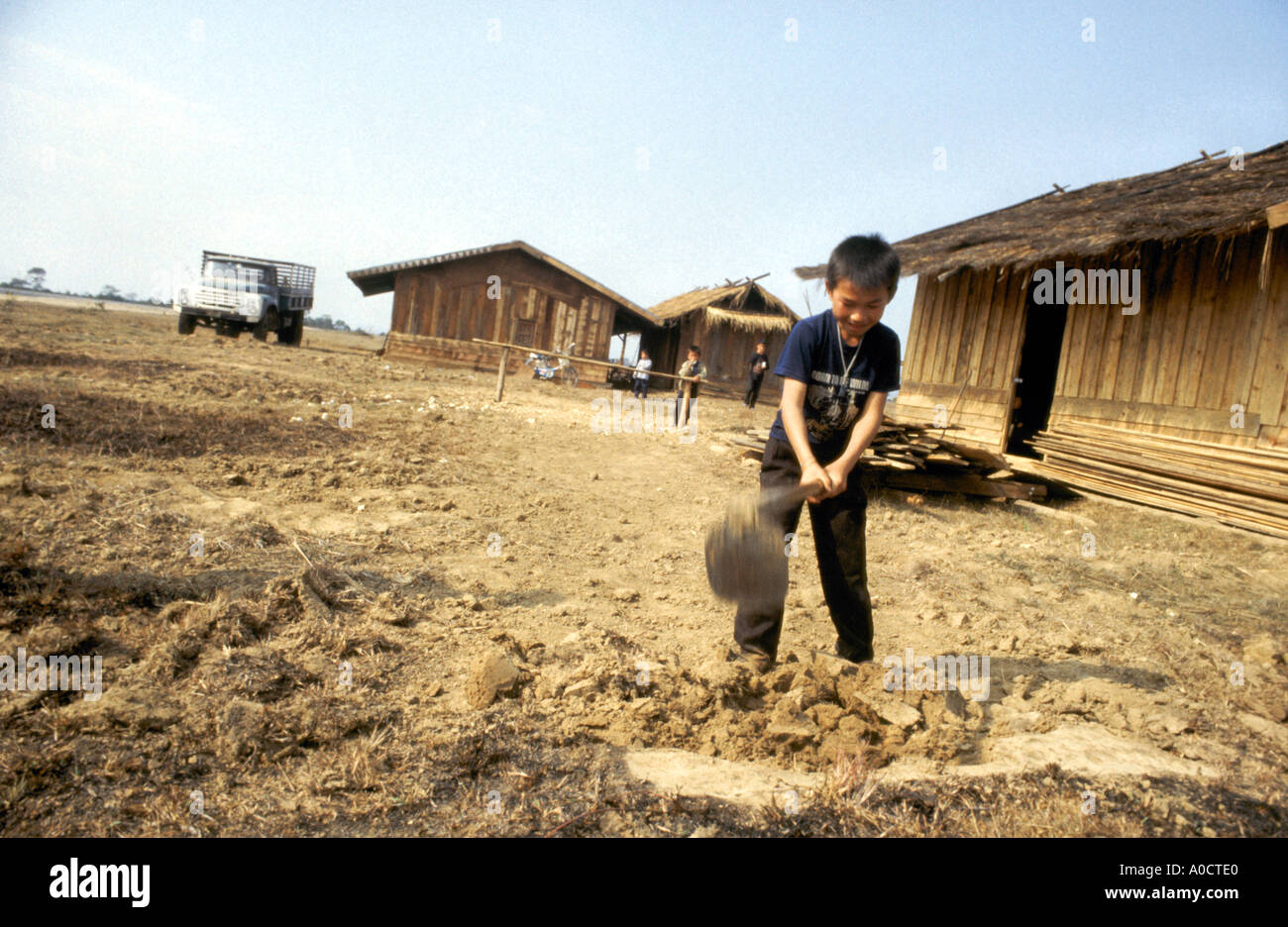 Un moment potentiellement mortels comme un garçon utilise une houe à ses parents ferme sur la Plaine des Jarres dans le nord du Laos Banque D'Images