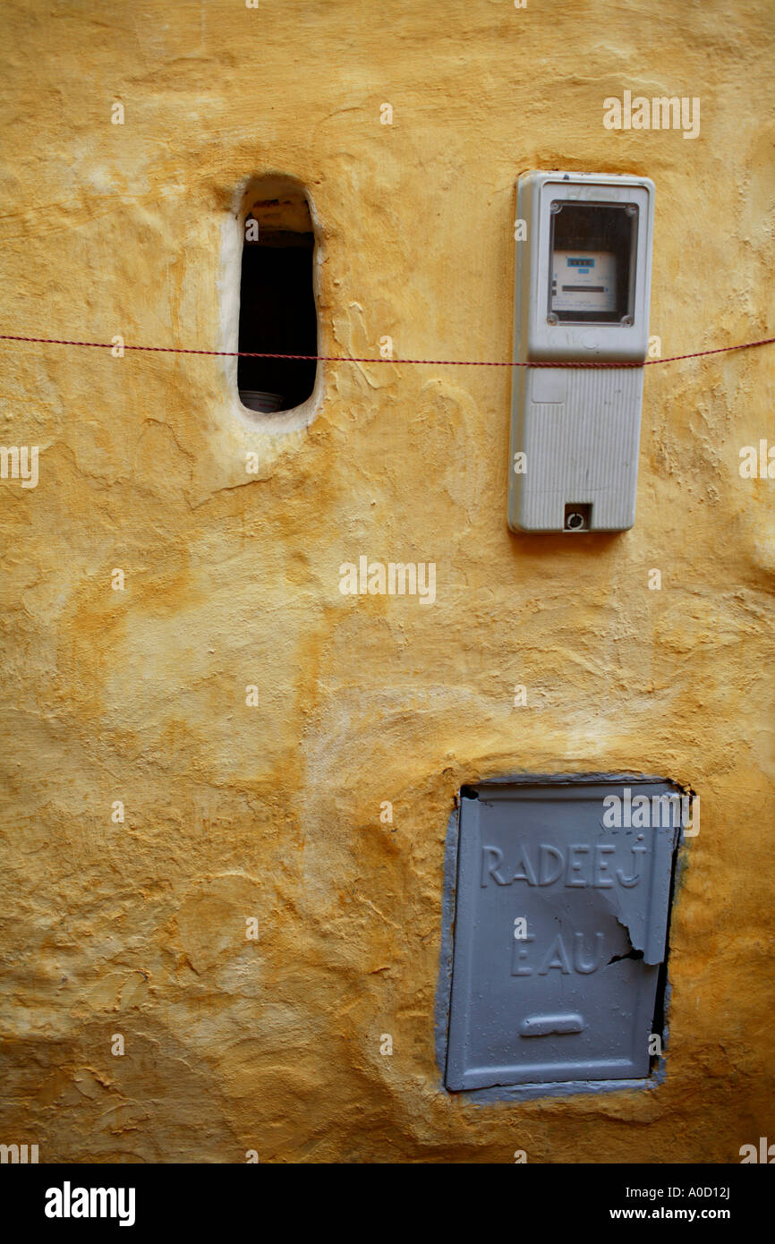 Un compteur d'eau et couvercle sur un mur peint en jaune dans la Médina d'El Jadida au Maroc Banque D'Images
