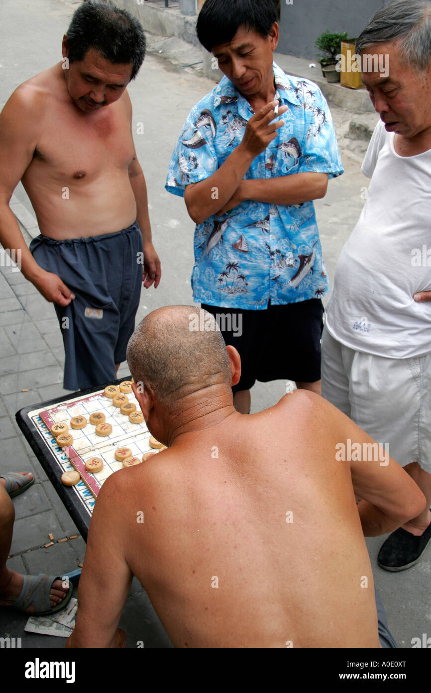 Trois hommes de regarder un jeu en cours, dans les rues de d'un Hutong de Beijing. Banque D'Images