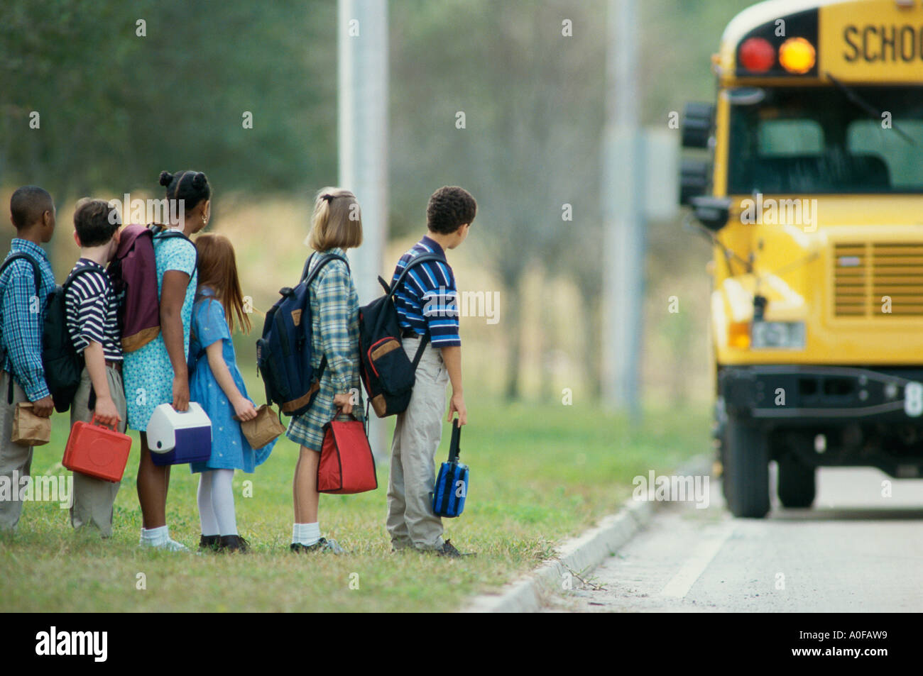 Profil de côté d'étudiants attendre en ligne pour un autobus scolaire Banque D'Images