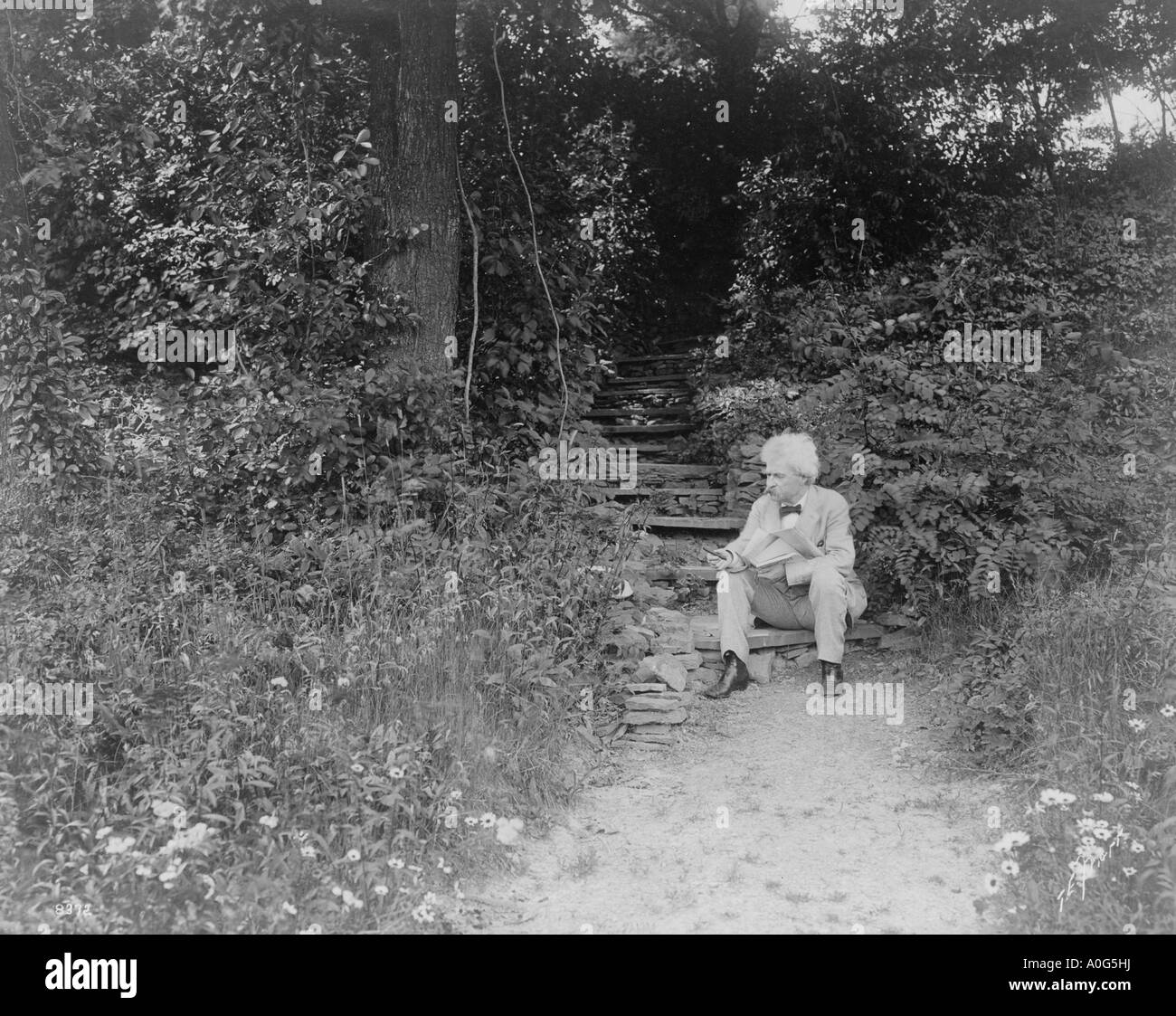 Un portrait de Mark Twain assis sur un pas vers la gauche en plein air holding cigar Banque D'Images