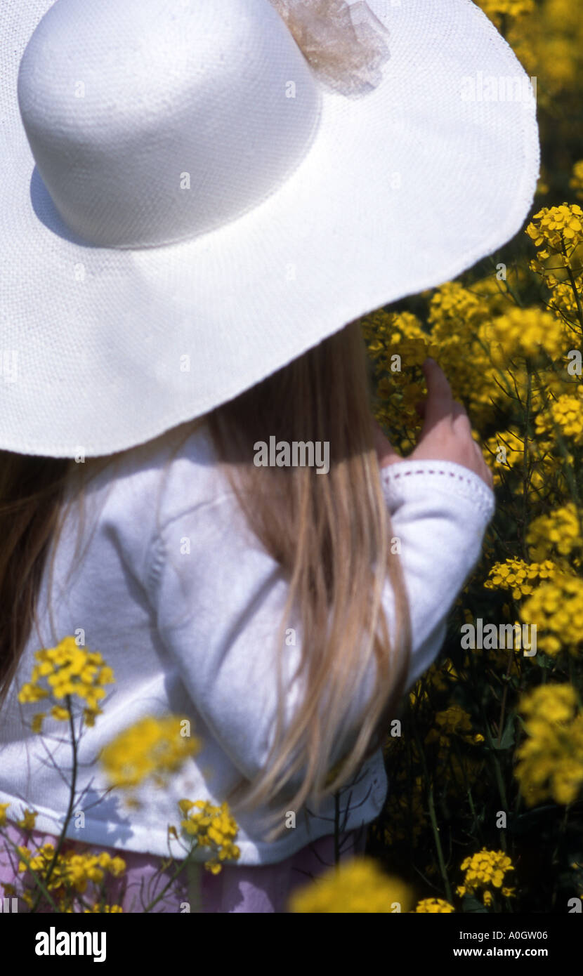 Girl in white hat disquette fonctionnant en fleurs de colza jaune Banque D'Images