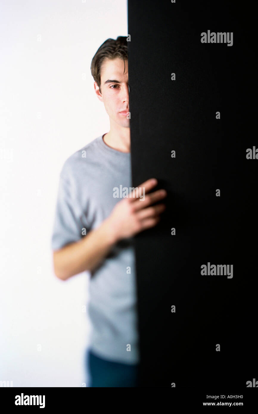 Portrait d'un jeune homme de se cacher derrière une porte Banque D'Images