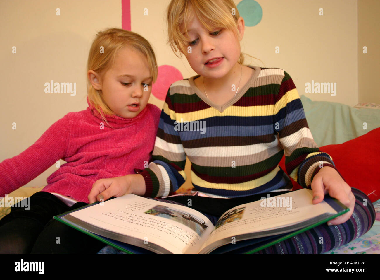 Soeurs de la lecture d'un livre d'ensemble à la maison Banque D'Images