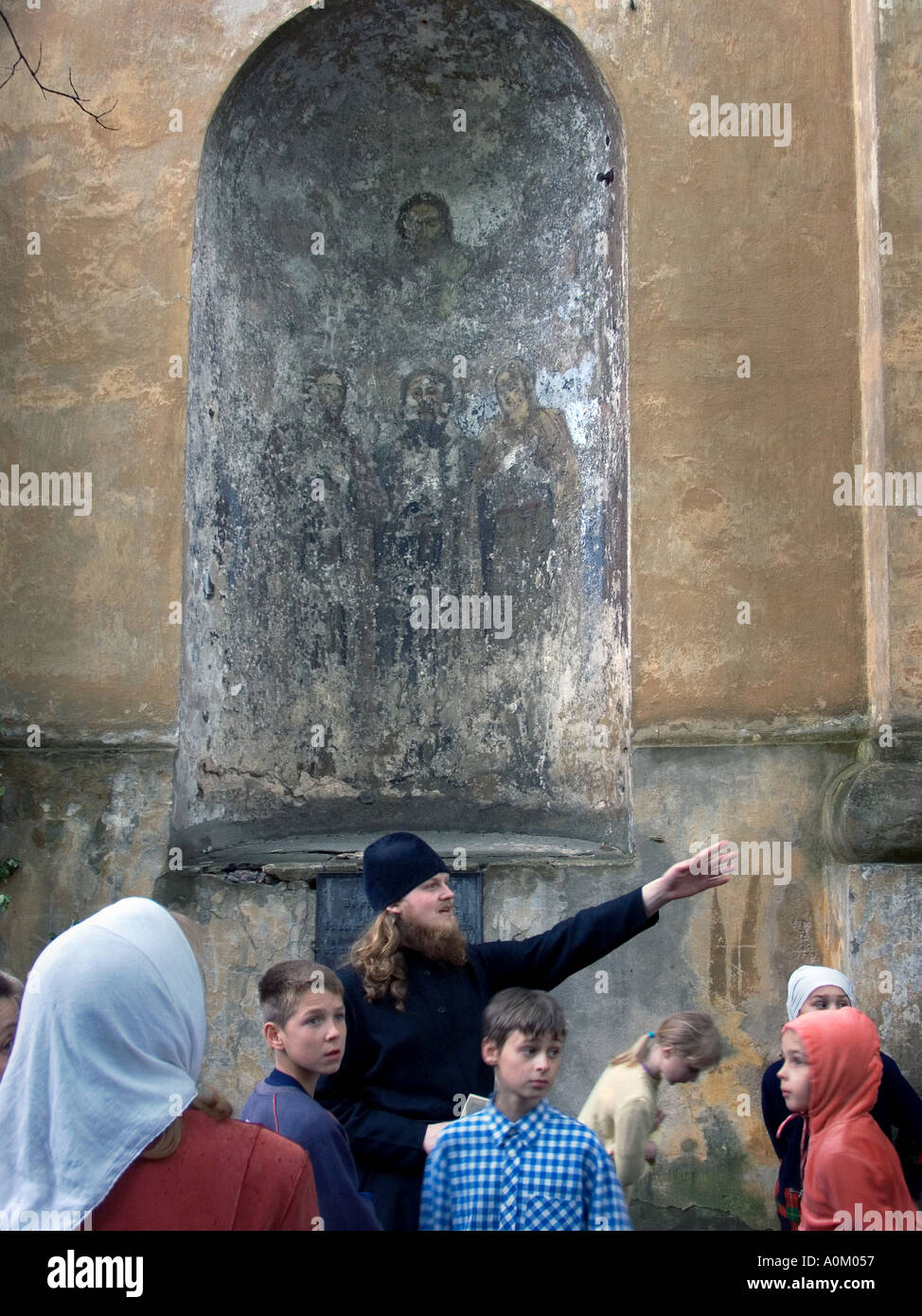 Prêtre orthodoxe russe par la collecte en face de la peinture religieuse en décomposition de Jésus Vilnius Lituanie Banque D'Images