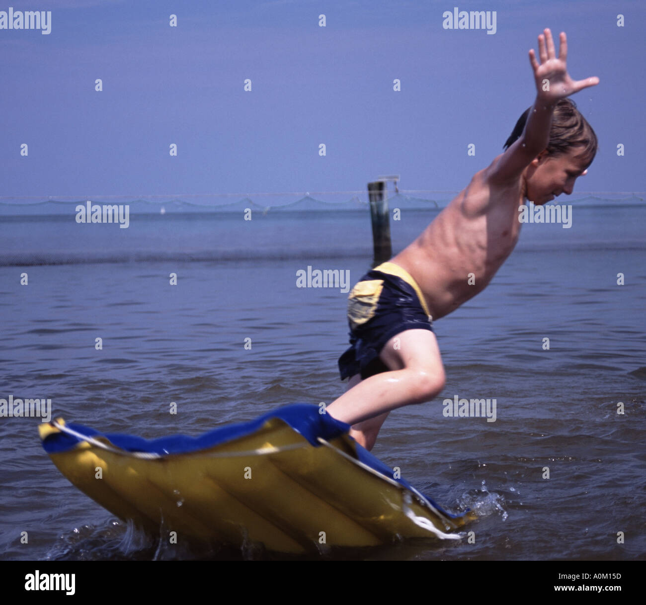 Jeune garçon sautant d'un radeau à l'eau à Breezy Point Maryland USA Banque D'Images