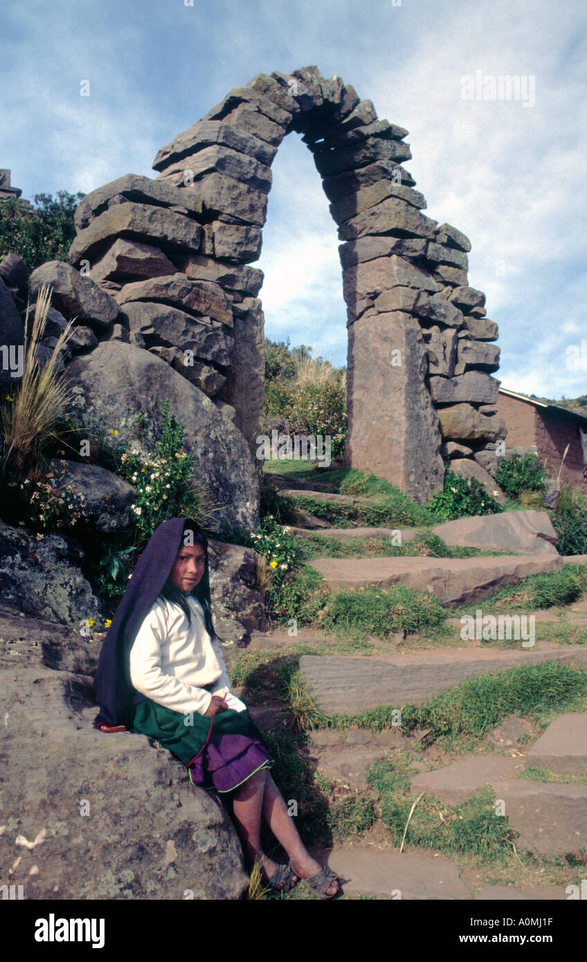 Jeune fille debout à côté d'une arche en pierre sur l'île de Taquile sur le lac Titicaca au Pérou Banque D'Images