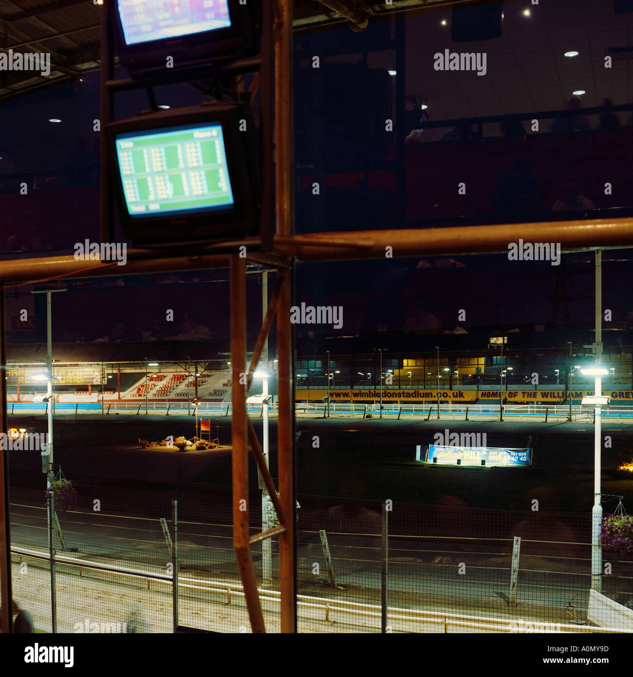 Tir intérieur de nuit de la piste de course du stade Greyhound de Wimbledon, sud de Londres, Angleterre en 2004, inc réflexions des joueurs dans les fenêtres Banque D'Images