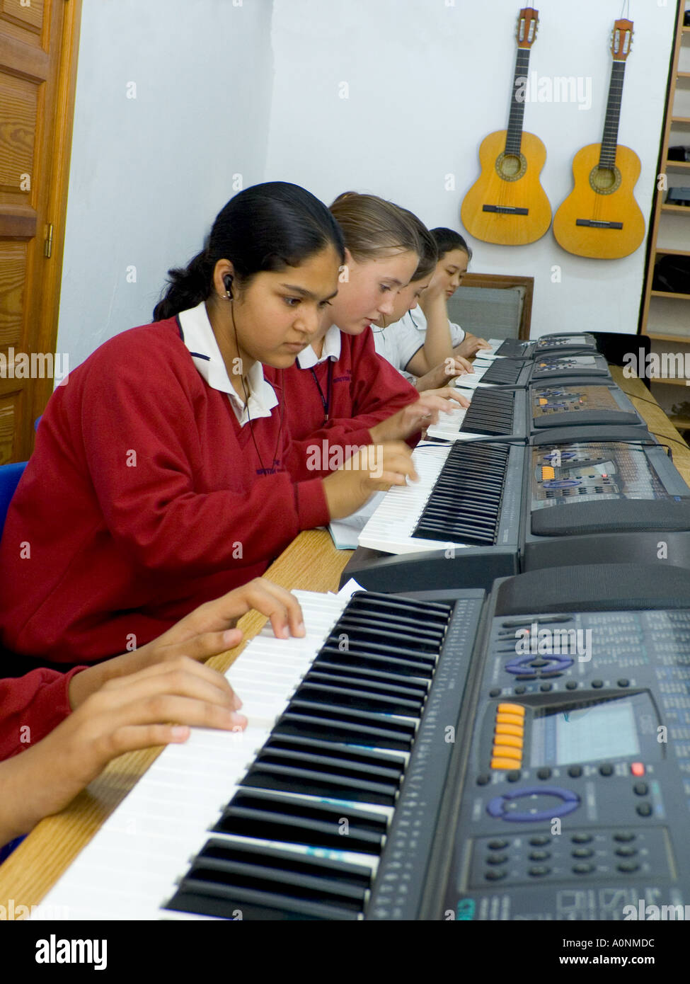 CLAVIER DE CLASSE MUSICALE les adolescents qui portent des écouteurs  s'entraîner et composer jouer des balances ensemble sur des pianos  électroniques dans une salle de classe de musique d'école Photo Stock -