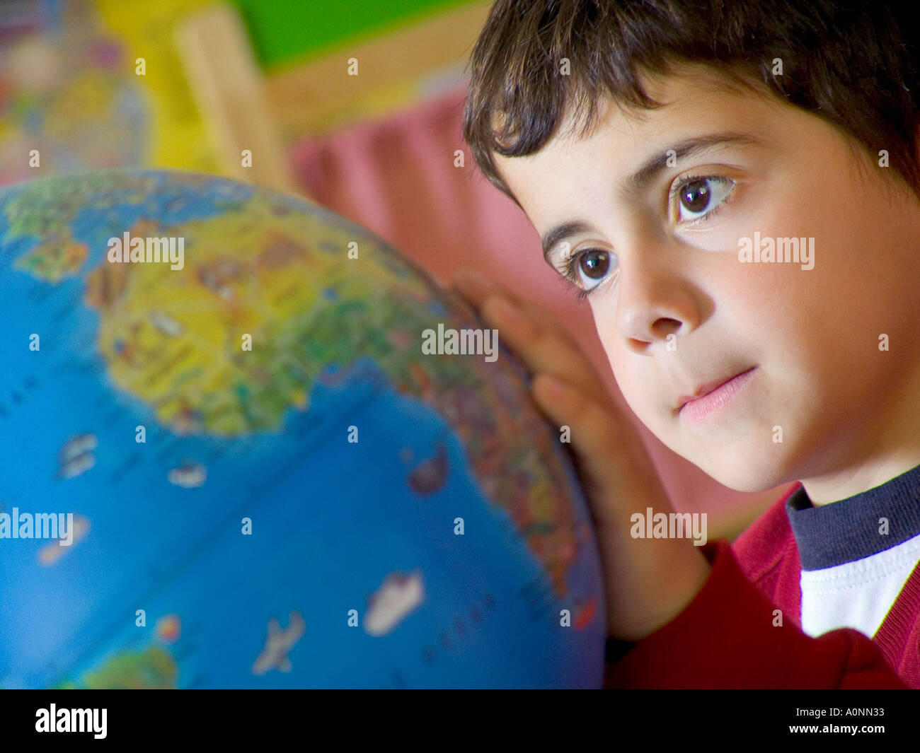 Fermer la vue sur la garçon à l'école maternelle à la classe à l'atlas du monde Monde Banque D'Images