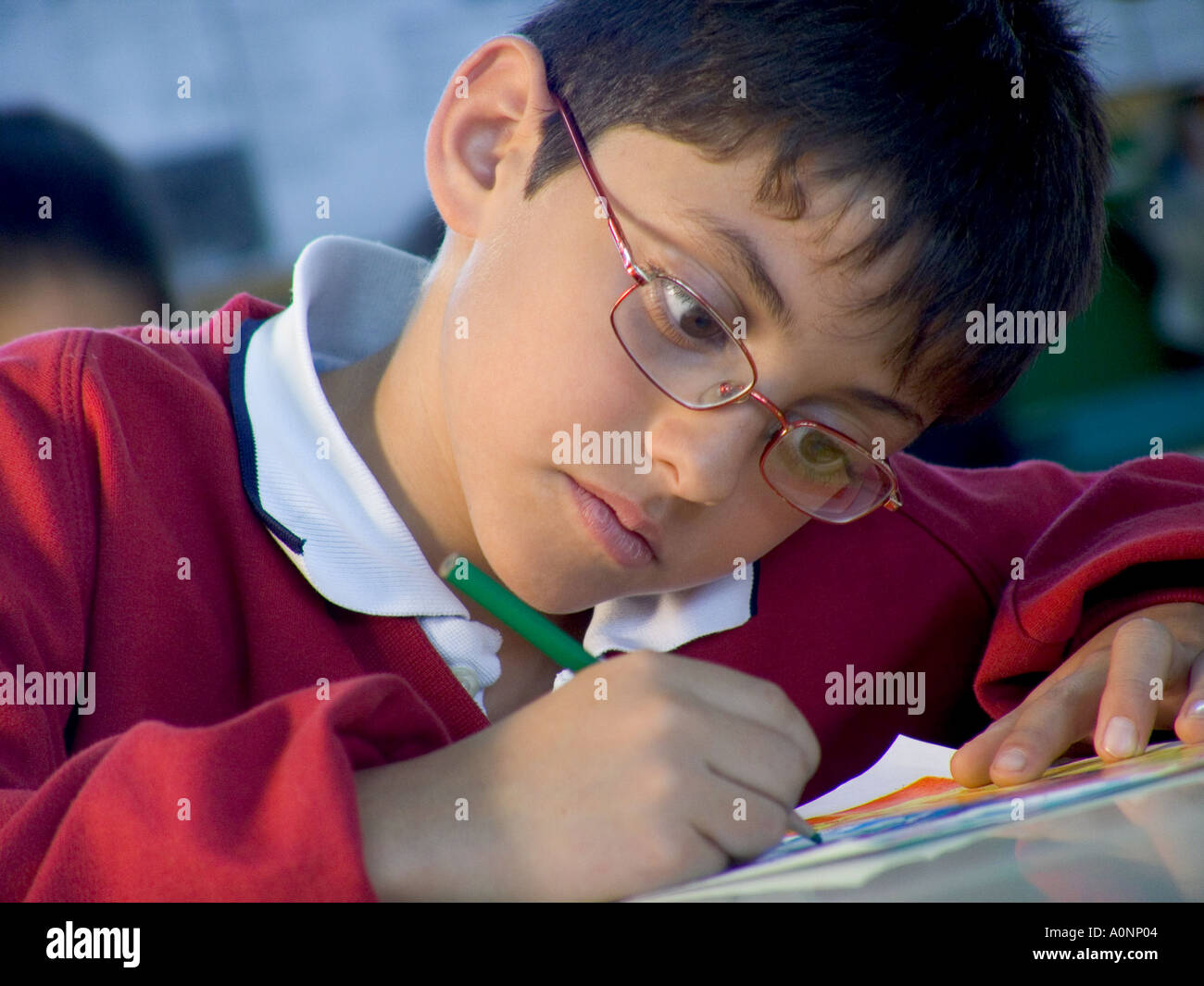 Garçon d'école junior élève 7-9 ans portant des lunettes se concentrant sur son écriture manuscrite et l'art dans l'éducation scolaire apprentissage de la situation en classe Banque D'Images