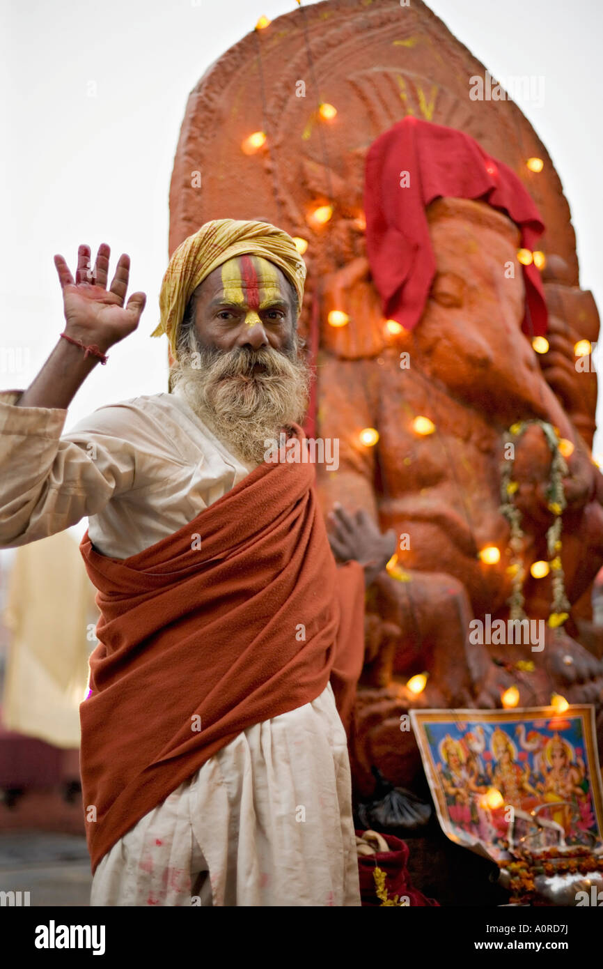 Saint homme soulève une main devant une statue de Ganesh drapés dans fairy lights au festival hindou de Pashupatinath Shivaratri Banque D'Images