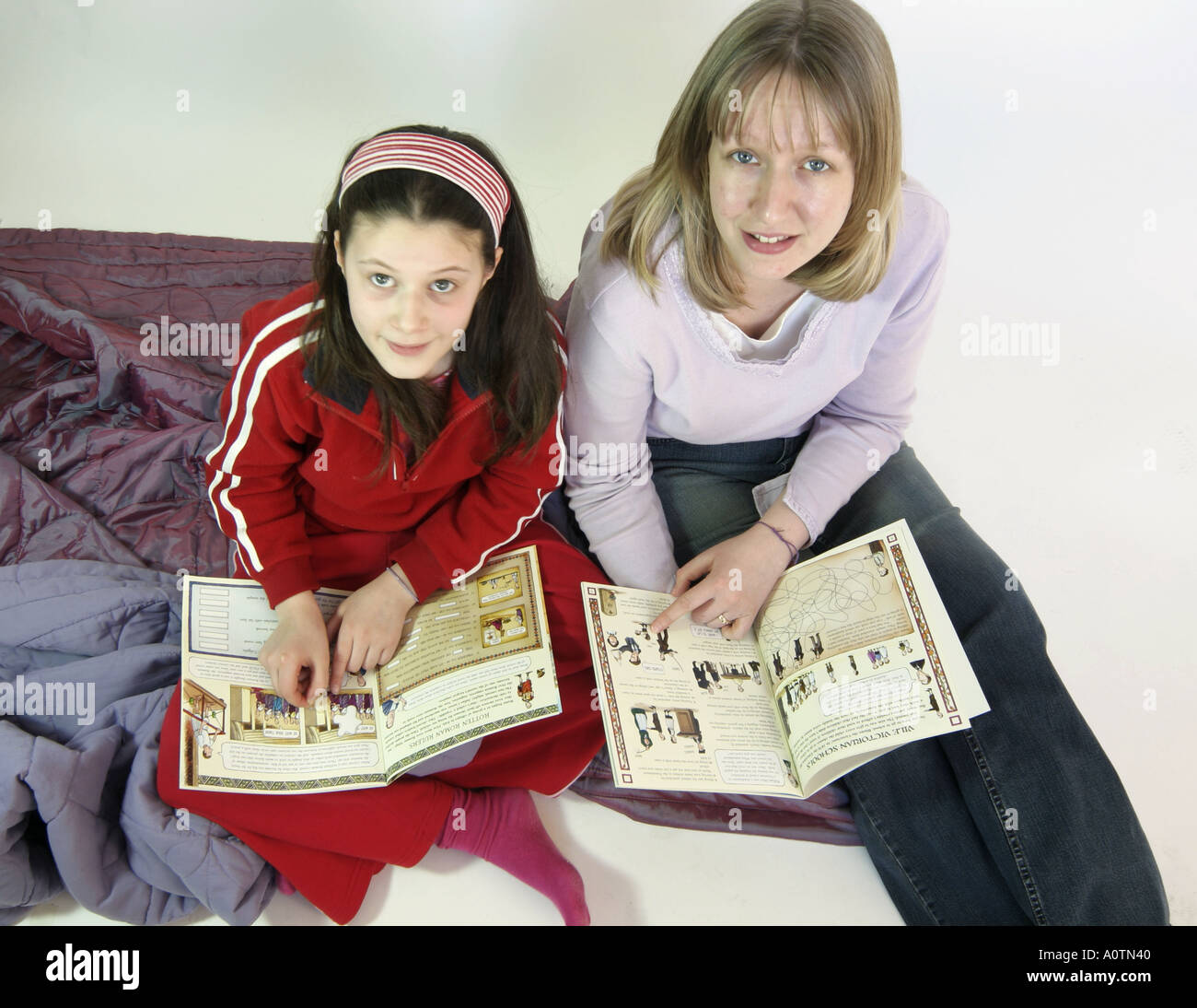 Jeune fille et femme mi 20s'est assis avec des livres à la ferme à l'appareil photo Banque D'Images