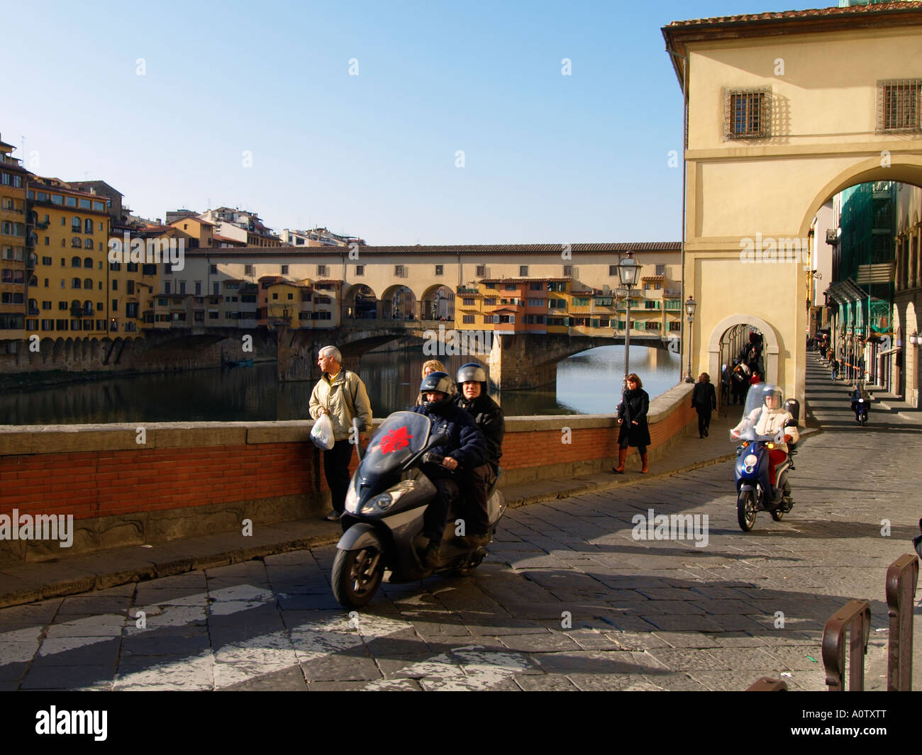 Des scooters à cheval le long de la rivière Arno et le Ponte Vecchio en arrière-plan Florence Toscane Italie Banque D'Images