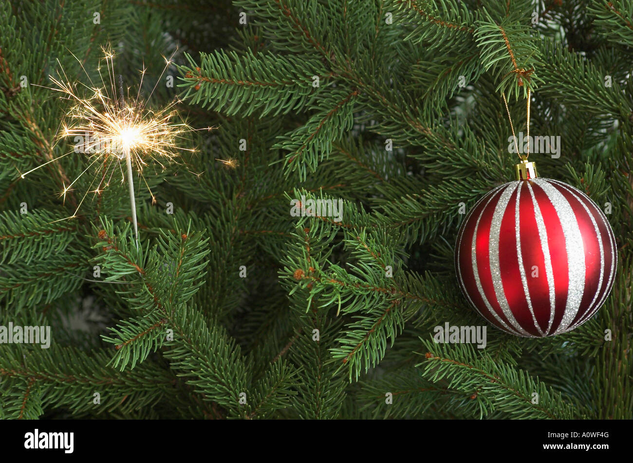 Sparkler et babiole rouge sur l'arbre de Noël Banque D'Images
