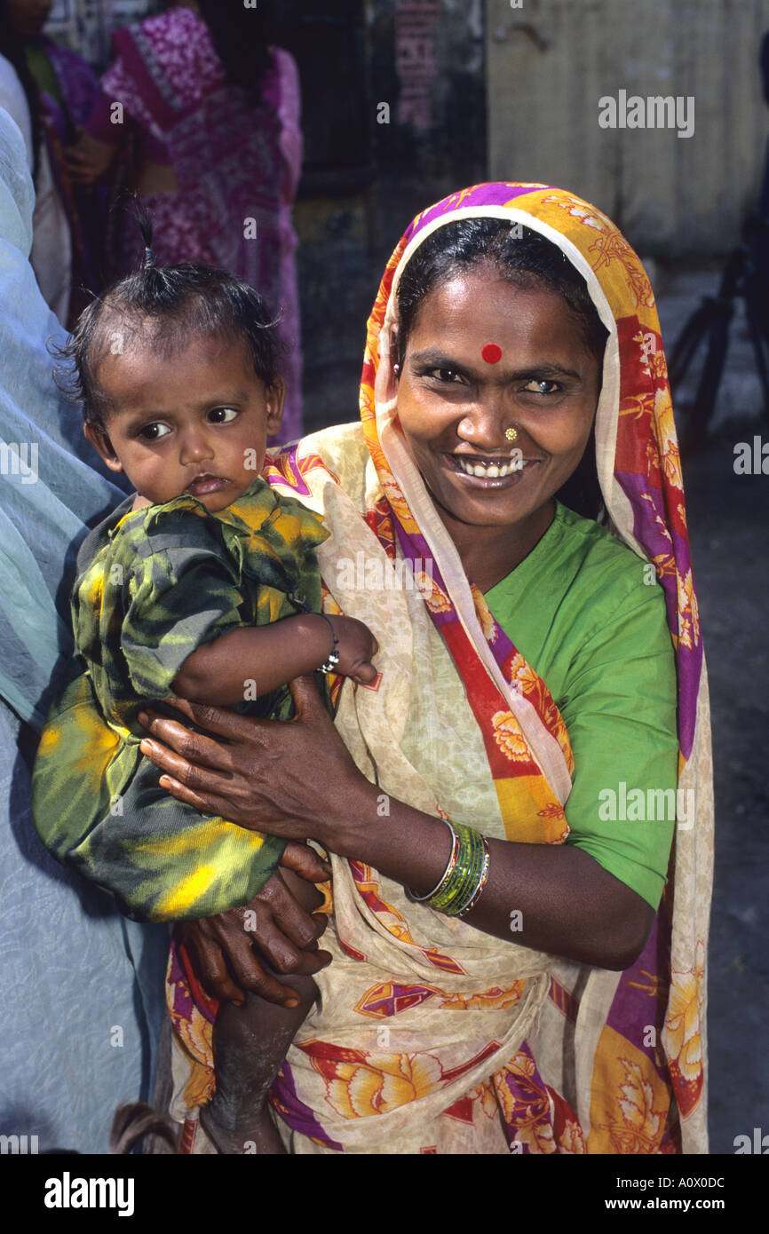 Femme tenant un bébé indien à New Delhi Inde En attente de livraison du lait gratuit Banque D'Images