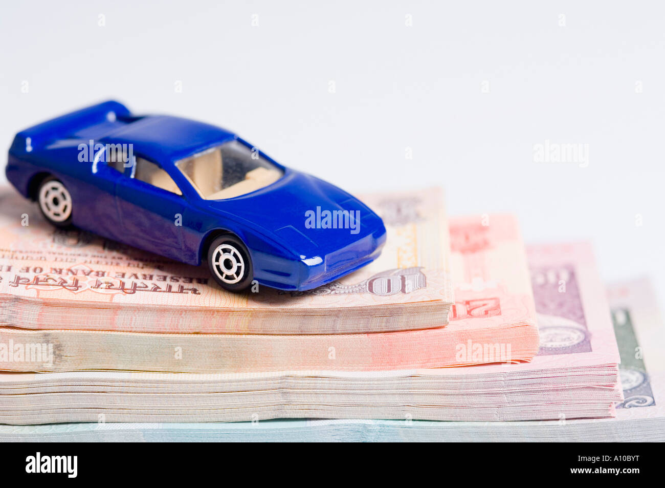 Close-up d'une petite voiture sur une pile de billets de différentes dénominations indiennes Banque D'Images