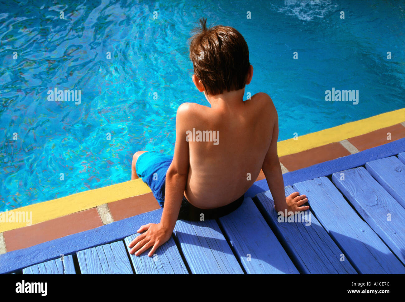 Garçon 8 à 10 ans, assis sur le bord de la piscine Banque D'Images