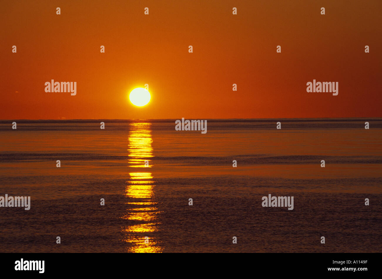 La chute de l'ENSEMBLE DU SUN se déverse les eaux de bronze de l'OCÉAN ALORS QUE LE CIEL devient orange Banque D'Images