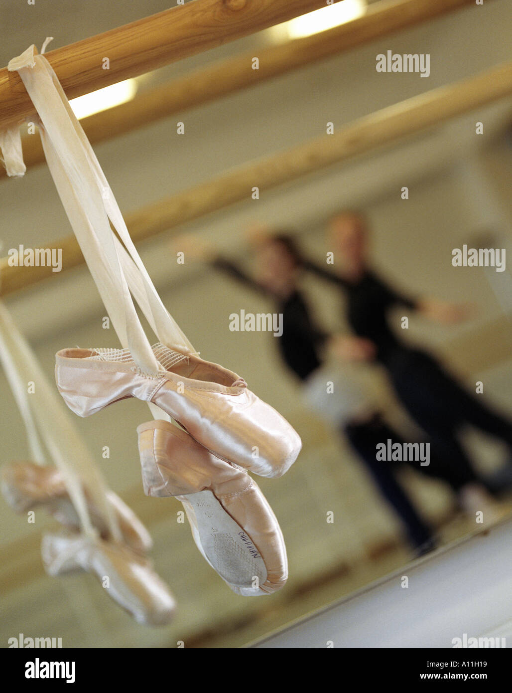 Une paire de chaussures de ballet pendaison avec deux ballerines dansant dans le bckground dans un studio au Royal Opera House Covent garden Banque D'Images