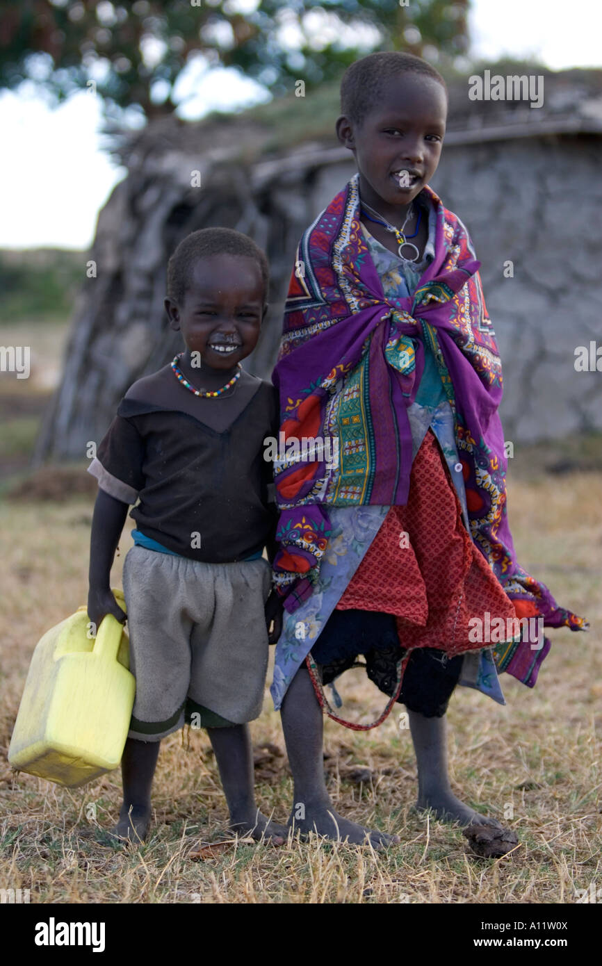 Deux enfants massaïs souriant au transport de l'eau pour leur village de Maasai Mara au Kenya Banque D'Images
