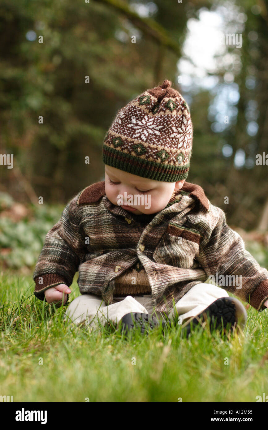 Bébé assis à l'extérieur dans l'herbe Banque D'Images