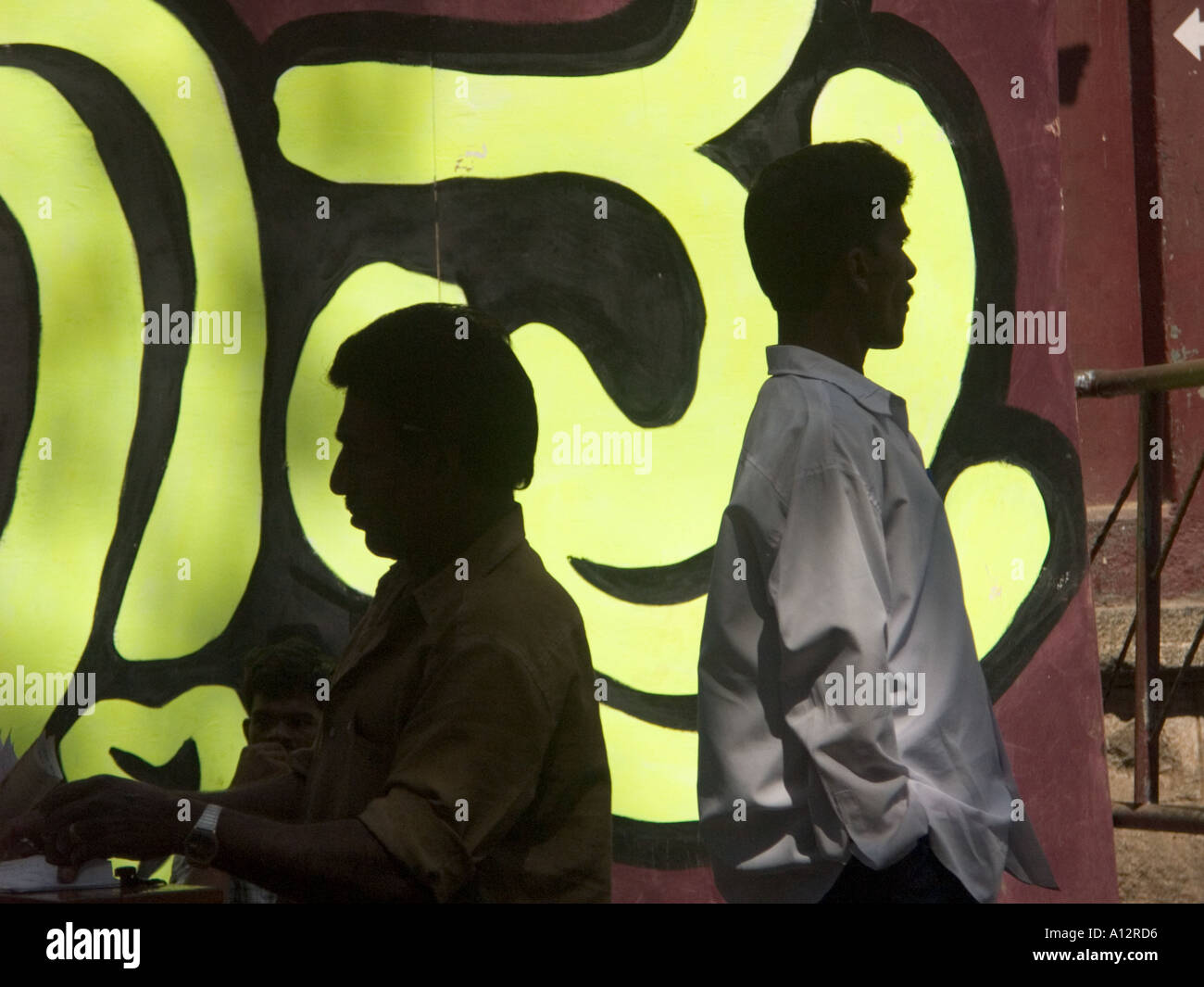 Les hommes debout devant une affiche de film indien Banque D'Images