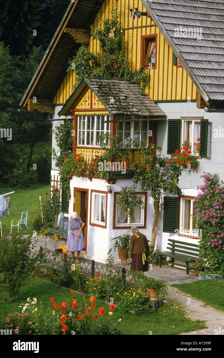 Deux dames à l'extérieur d'une maison typique avec des fleurs d'été dans windowboxes et dans le jardin dans la région de Salzkammergut Autriche Un Banque D'Images