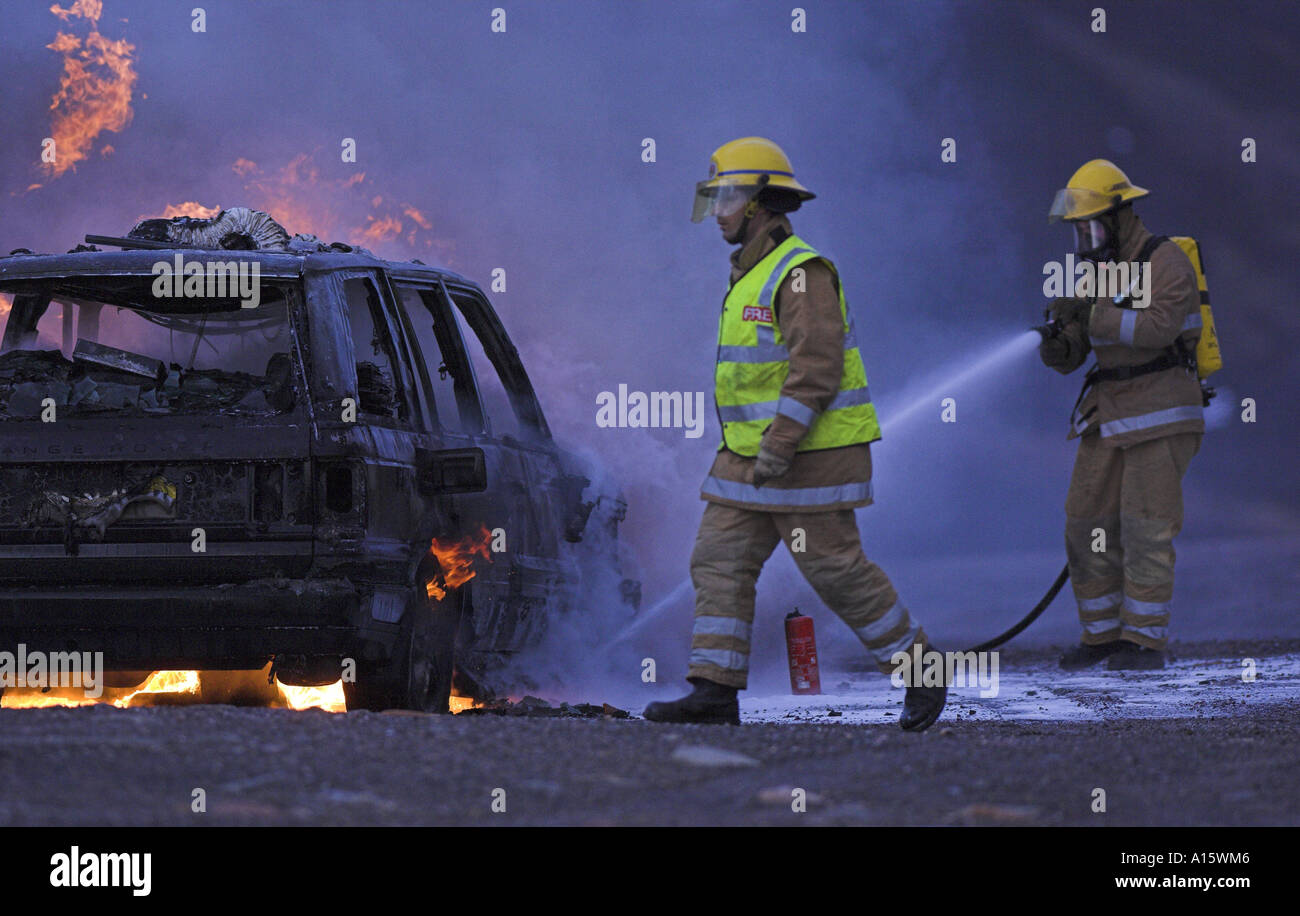 Les pompiers sur le lieu d'une voiture en flammes. Banque D'Images
