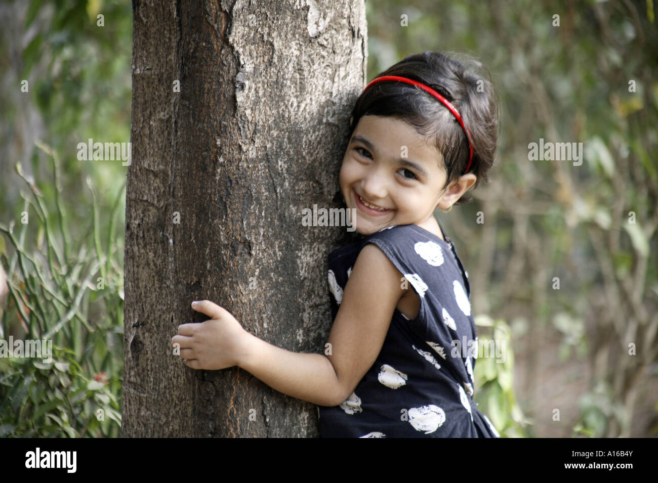 Jeune Indien little girl hugging a tree in Bombay Mumbai Inde Banque D'Images