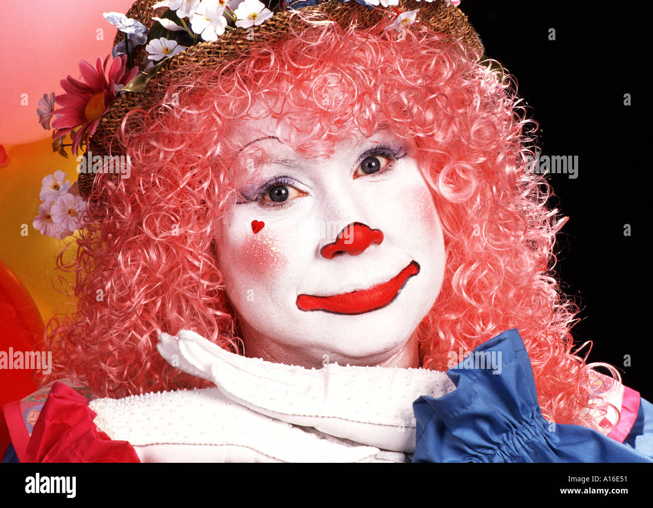Clown femelle de cheveux rose avec un visage blanc et sourire Banque D'Images