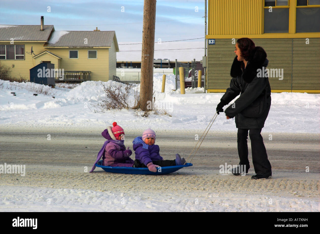 Femme inuit tirant ses enfants en traîneaux dans l'Arctique village de Kuujjuaq Banque D'Images