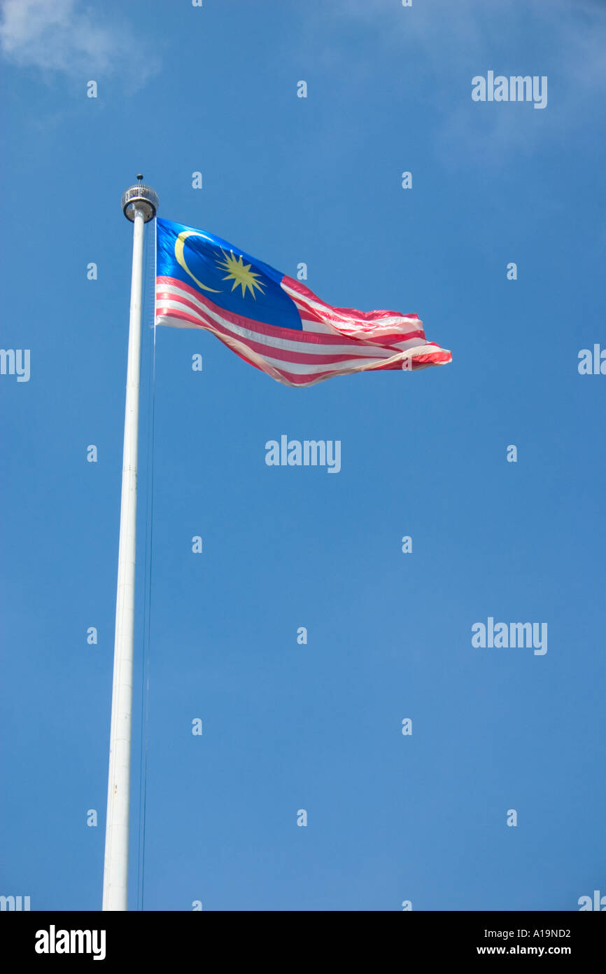 De brandir le drapeau de la Malaisie dans l'air contre le ciel bleu Banque D'Images