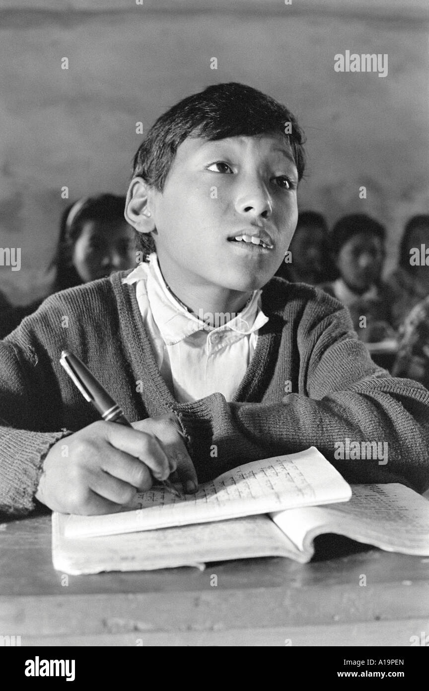 B/W d'un garçon Sherpa écrivant à son bureau dans la salle de classe d'une école distante de l'Himalaya à Solukhumbu, au Népal Banque D'Images