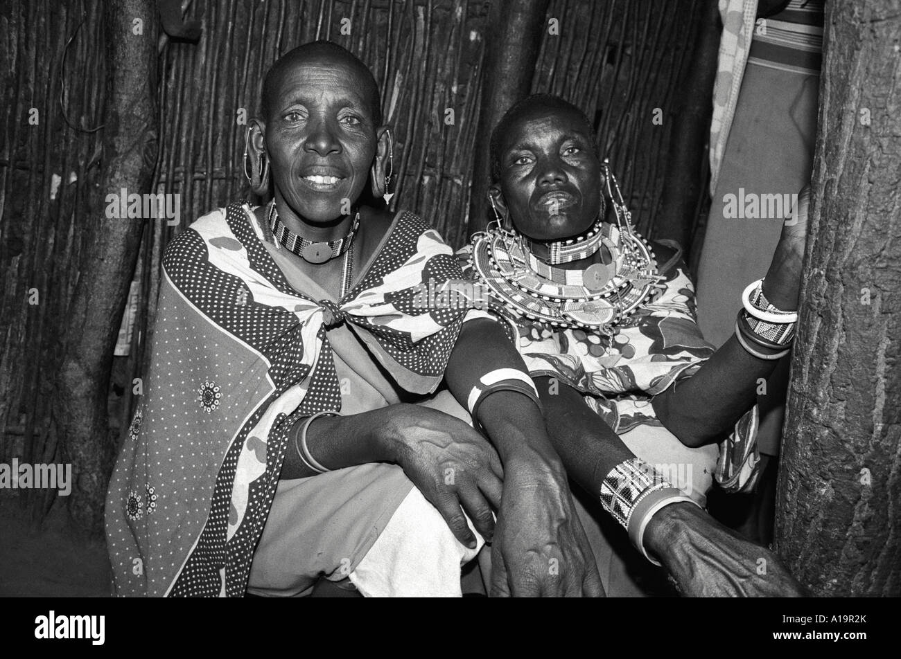 Portrait en noir et blanc de deux sœurs Maasai en robe traditionnelle et bijoux assis dans leur maison faite à partir de méteries traditionnelles. Kajiado, Kenya Banque D'Images